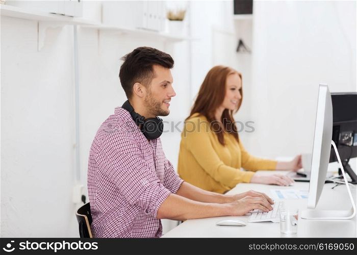 business, startup, education, technology and people concept - happy creative team or students with headphones and computer at office