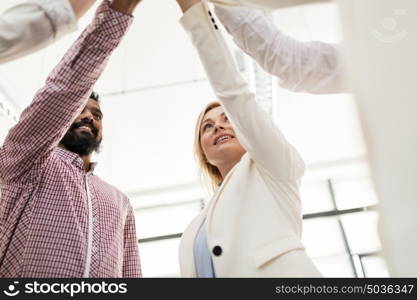 business, startup, gesture, people and teamwork concept - happy creative team making high five at office. happy business team making high five at office