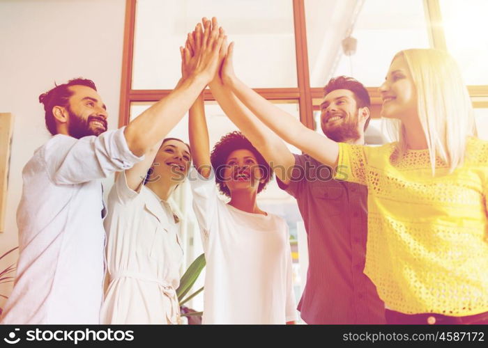 business, startup, gesture, people and teamwork concept - happy creative team making high five in office