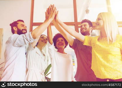 business, startup, gesture, people and teamwork concept - happy creative team making high five in office