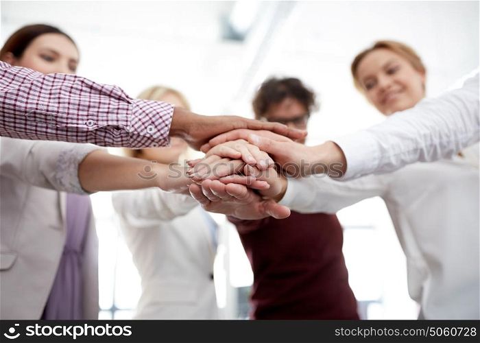 business, startup, gesture, people and teamwork concept - happy creative team with hands on top of each other at office. happy business team with hands on top at office