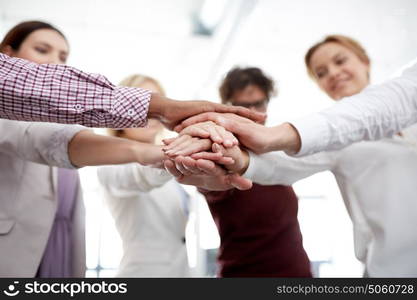 business, startup, gesture, people and teamwork concept - happy creative team with hands on top of each other at office. happy business team with hands on top at office