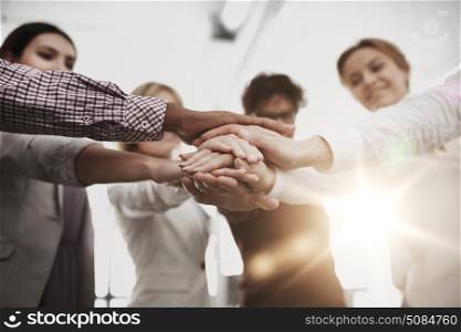 business, startup, gesture, people and teamwork concept - happy creative team with hands on top of each other at office. happy business team with hands on top at office. happy business team with hands on top at office
