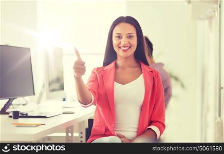 business, startup, gesture, success and people concept - happy young african woman with computer working at office showing thumbs up. happy african woman showing thumbs up at office