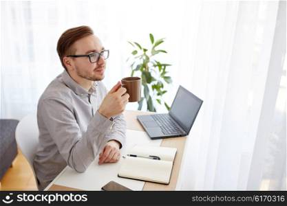 business, startup, inspiration and people concept - happy businessman or creative male worker with notebook or diary drinking coffee and thinking at home office
