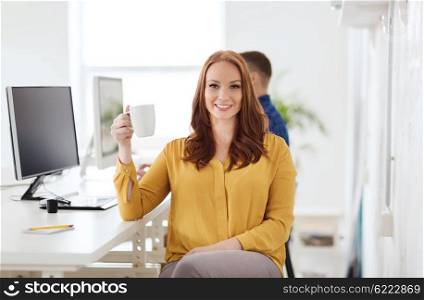 business, startup, people and break concept - happy businesswoman drinking coffee or tea at office