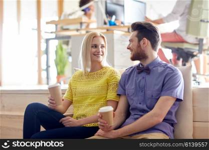 business, startup, people and communication concept - happy man and woman drinking coffee and talking in office