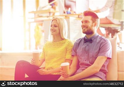 business, startup, people and communication concept - happy man and woman drinking coffee in office