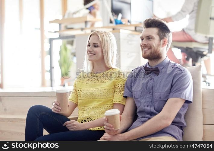business, startup, people and communication concept - happy man and woman drinking coffee in office