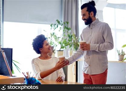 business, startup, people and drinks concept - happy latin man bringing coffee to african woman in office