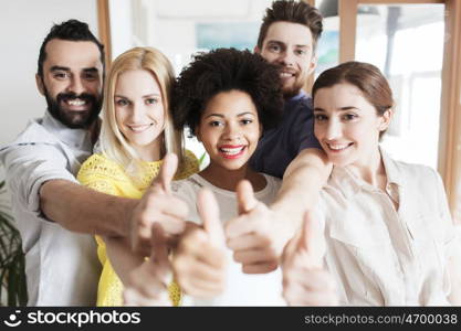 business, startup, people and teamwork concept - happy creative team showing thumbs up in office