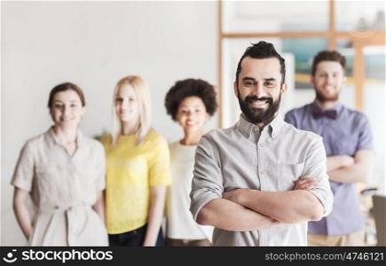 business, startup, people and teamwork concept - happy young man with beard over creative team in office