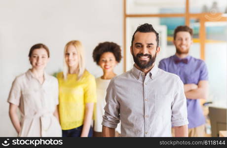 business, startup, people and teamwork concept - happy young man with beard over creative team in office