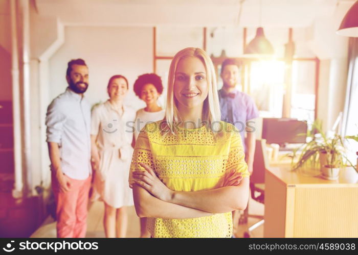 business, startup, people and teamwork concept - happy young woman over creative team in office