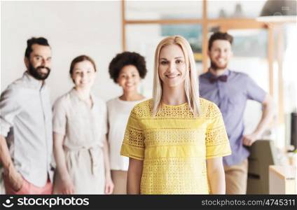 business, startup, people and teamwork concept - happy young woman over creative team in office