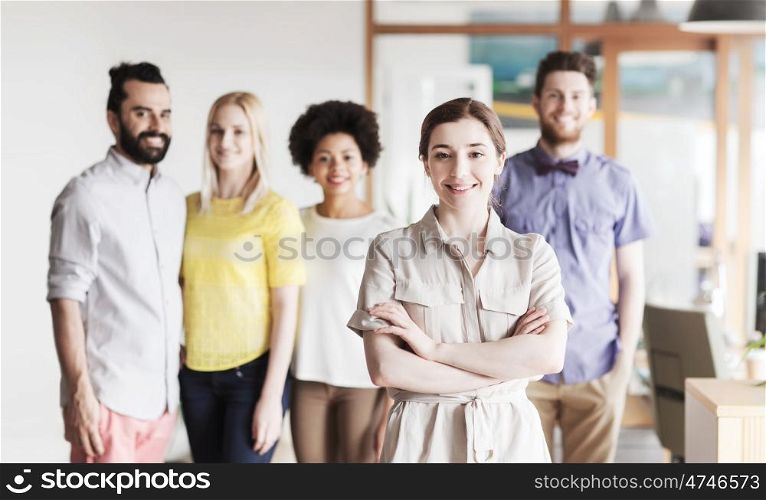 business, startup, people and teamwork concept - happy young woman over creative team in office