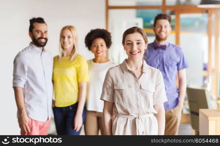 business, startup, people and teamwork concept - happy young woman over creative team in office