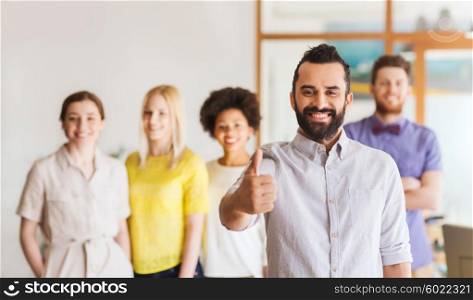 business, startup, people, gesture and teamwork concept - happy young man with beard showing thumbs up over creative team in office