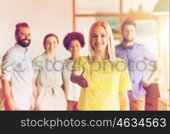 business, startup, people, gesture and teamwork concept - happy young woman greeting by handshake over creative team in office