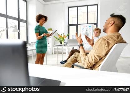 business, startup, planning and people concept - woman with tablet pc computer and creative team at office conference or presentation. woman with tablet pc and creative team at office. woman with tablet pc and creative team at office