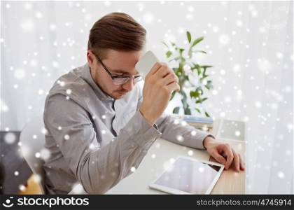 business, startup, stress, problem and people concept - businessman or creative male worker with smarphone at home office over snow