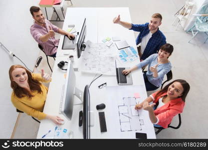 business, startup, success and people concept - creative team with computers, blueprint and scheme showing thumbs up at office