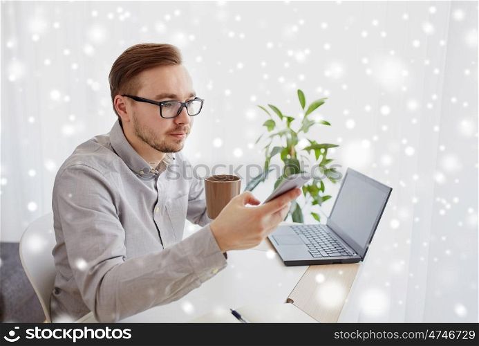 business, startup, technology and people concept - businessman or creative male worker texting on smarphone and drinking coffee at home office over snow