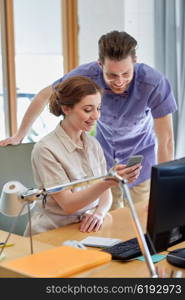 business, startup, technology and people concept - happy creative team with smartphone and computer in office