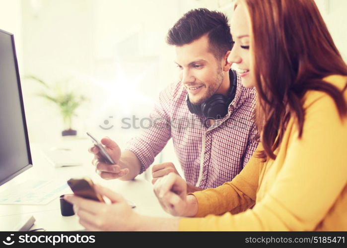 business, startup, technology and people concept - happy creative team with smartphones, computer and pen tablet at office. happy creative team with smartphones at office