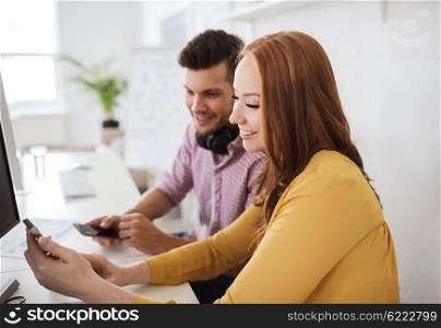 business, startup, technology and people concept - happy creative team with smartphones, computer and pen tablet at office
