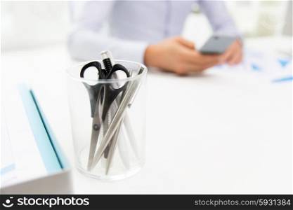 business, stationery and office supply concept - close up of organizer with scissors and pens over businessman sitting at table