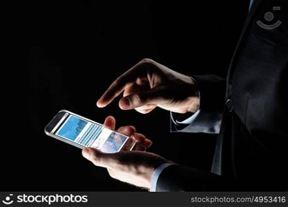 business, statistics, people and future technology concept - close up of businessman hands with charts on transparent smartphone screen over black background. close up of businessman with charts on smartphone