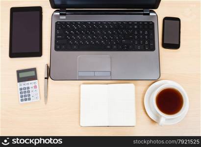 business still life - top view of laptop, tablet PC, smartphone, calculator, cup of tea, pen and notebook on office table