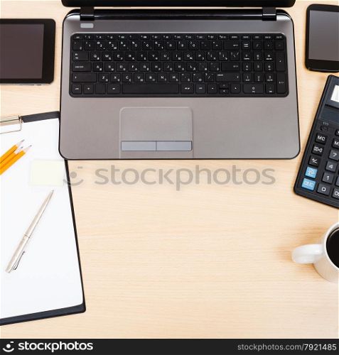 business still life - top view of laptop, tablet PC, smartphone, clipboard, calculator, mug of coffee, pen and pencil on office table