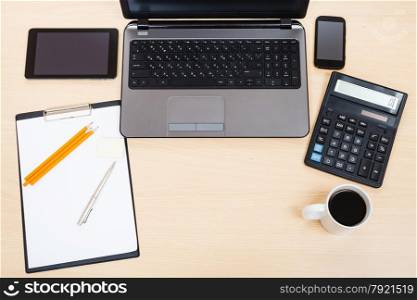 business still life - top view of laptop, tablet PC, smartphone, clipboard, calculator, cup of tea, pen and pencil on office table