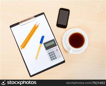 business still life - top view of smartphone, clipboard, calculator, cup of tea, pen and pencil on office table