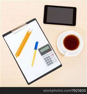 business still life - top view of tablet PC, clipboard, calculator, cup of tea, pen and pencil on office table