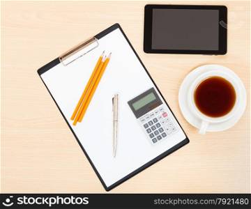 business still life - view of tablet PC, clipboard, financial calculator, cup of tea, pen and pencil on office table