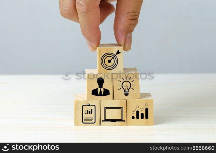 business strategy Action plan Goal and target icons with hand stack a wood cube block on a table. Copy space company development concept.