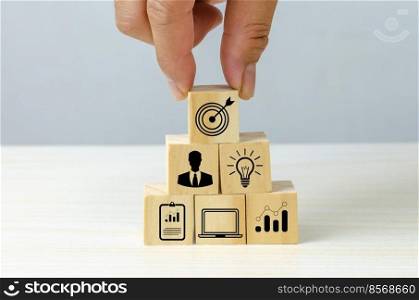 business strategy Action plan Goal and target icons with hand stack a wood cube block on a table. Copy space company development concept.