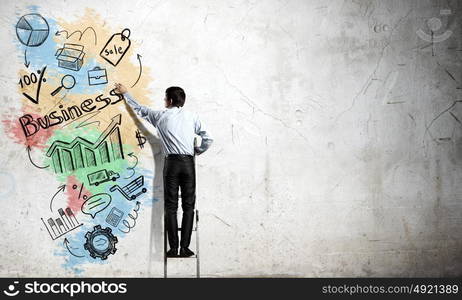 Business strategy and planning . Back view of businessman standing on ladder and drawing sketches on wall