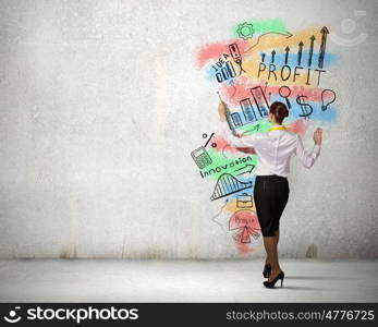 Business strategy and planning . Back view of businesswoman standing on ladder and drawing sketches on wall