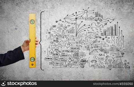 Business strategy. Close up of female hand with ruler and business sketches on wall