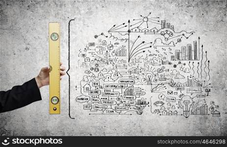 Business strategy. Close up of female hand with ruler and business sketches on wall