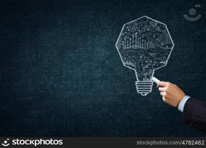 Business strategy. Close up of hand drawing light bulb with chalk
