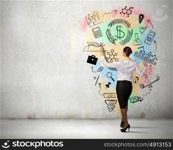 Business strategy planning. Back view of businesswoman drawing sketch on wall