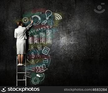 Business strategy planning. Back view of businesswoman standing on ladder and drawing sketch on wall