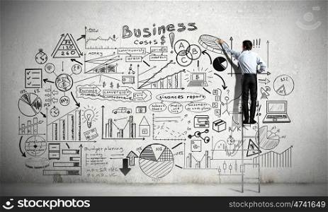 Business strategy presentation. Back view of businessman standing on ladder and drawing his great plan on wall