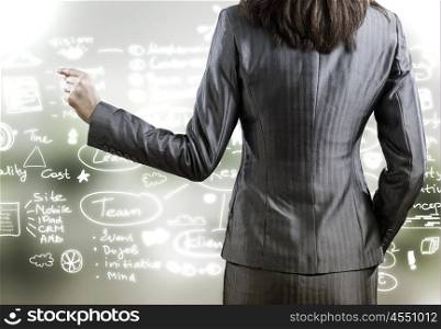 Business strategy. Rear view of businesswoman drawing business sketches with finger