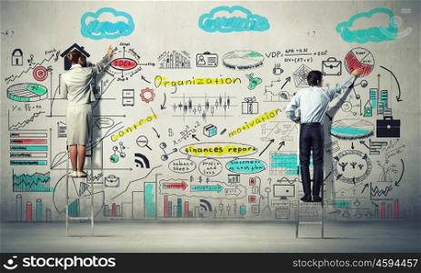 Business strategy seminar. Back view of businessman and businesswoman standing on ladder and drawing sketches on wall